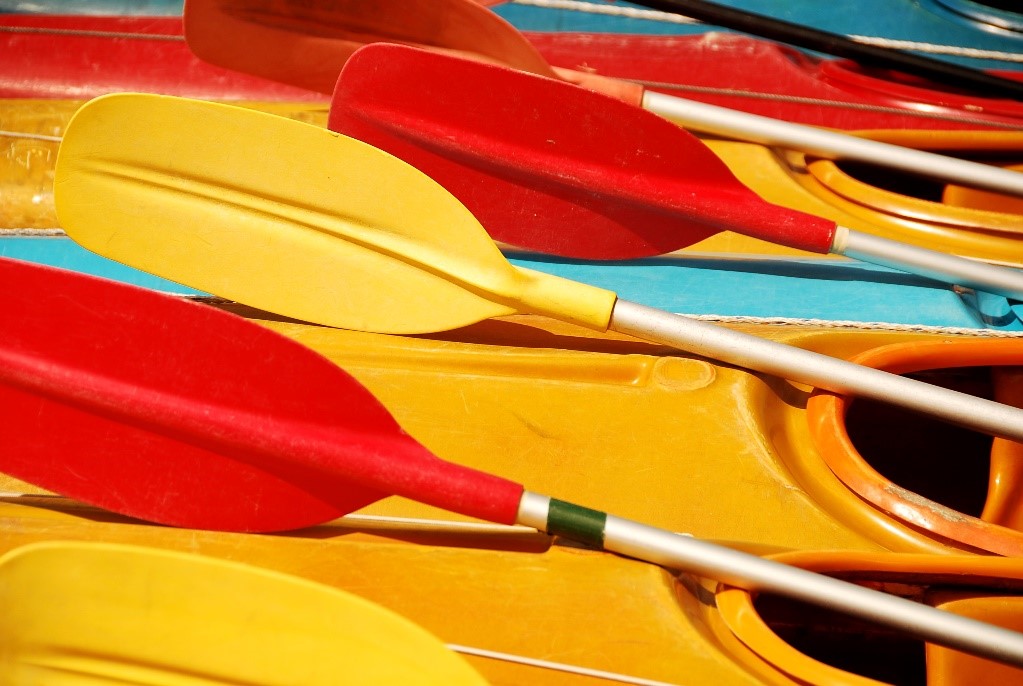 Five red and yellow rest on top of colorful kayaks